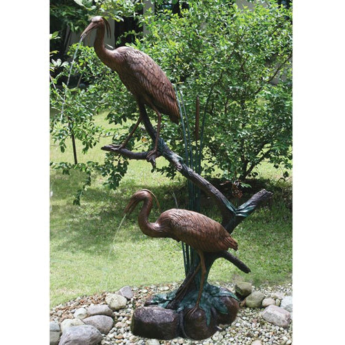 Pair of brass heron statues, one standing tall, the other with its head lowered, suitable for garden or pool decoration.