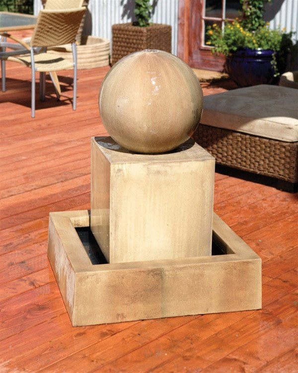 Garden water fountain with a block base and a sphere on top.