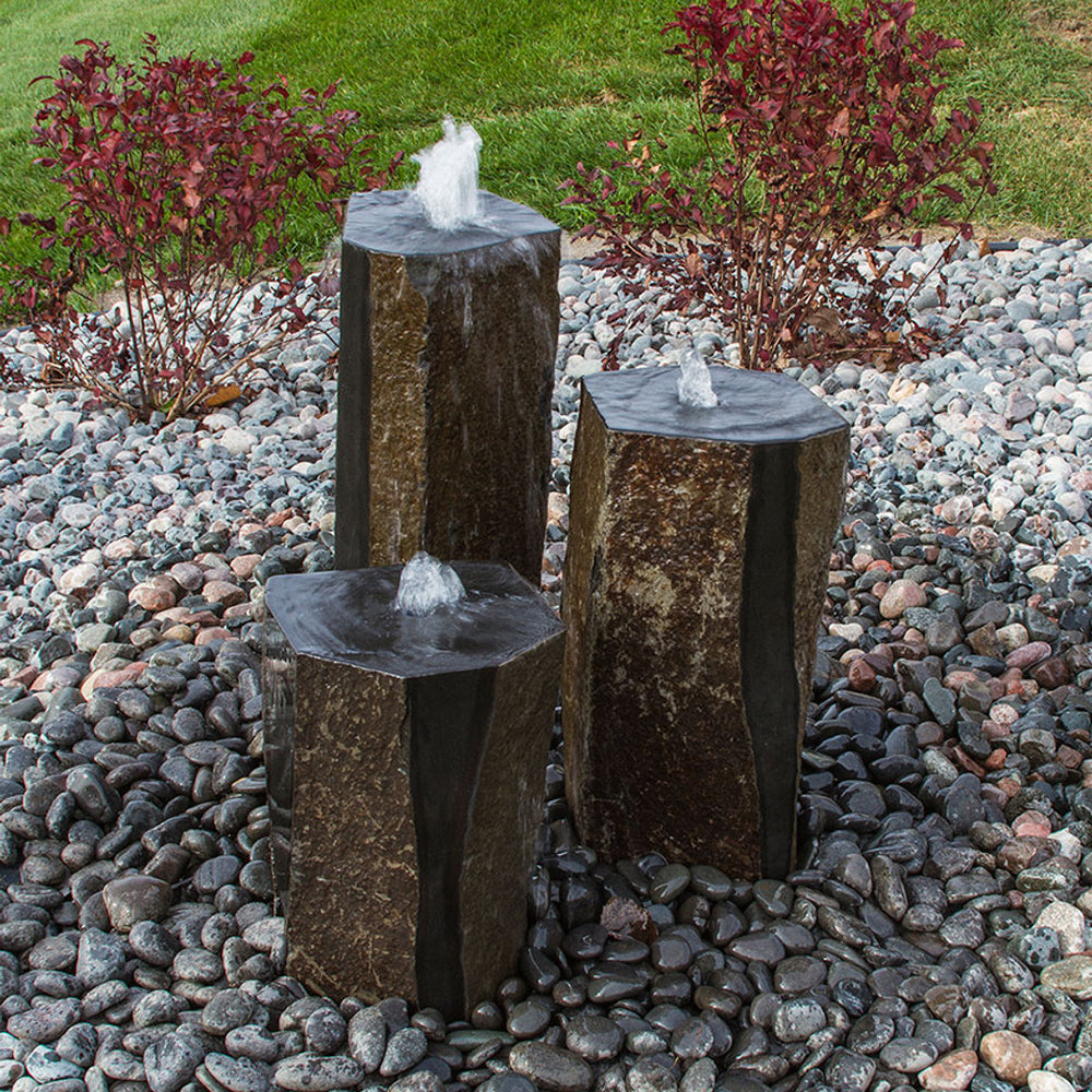 Semi-polished basalt rock column fountain with water flowing down its sides.