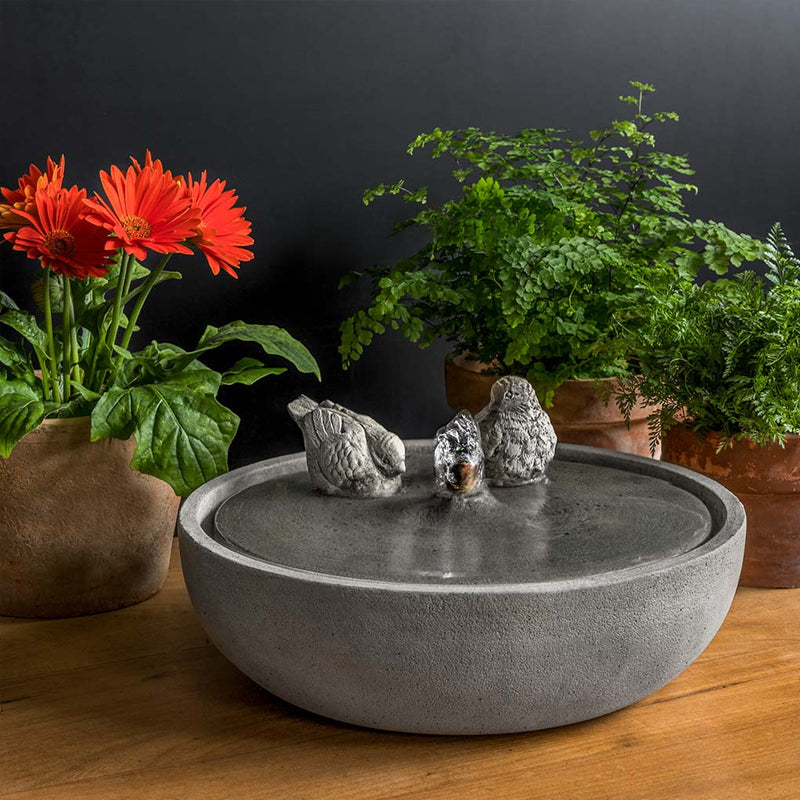 Tabletop fountain with a songbird perched on the edge.