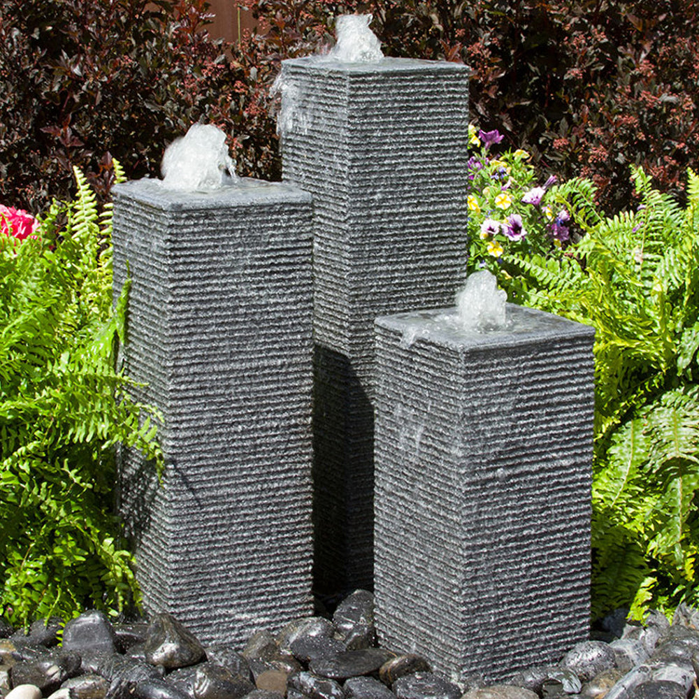Outdoor fountain with four square, chiseled stone towers.